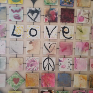 A mosaic of colorful tiles featuring hearts, peace signs, and abstract art, with four central tiles spelling 'LOVE' in bold letters.