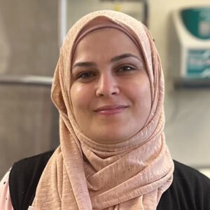 Fatouh Kablaan smiling, wearing a light pink hijab, with a neutral indoor background.