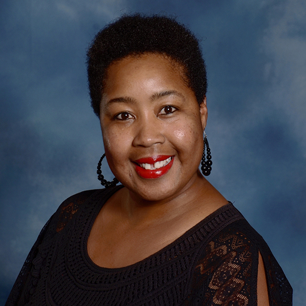 Francia Allen smiling in a black top with red lipstick, photographed against a blue background.