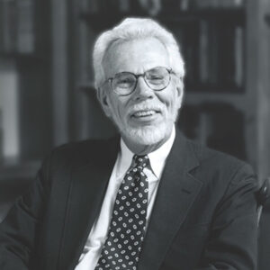 Rev. John B. Wolfe, an man with what hair and a beard, wearing a suit and tie, smiling warmly at the camera.