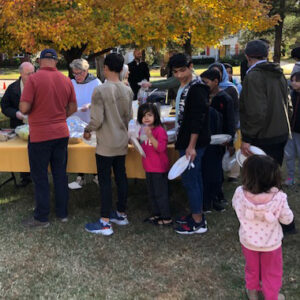 Church members welcoming Afghan families during an outdoor gathering with food.