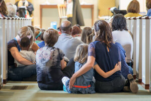 Children and families sit together on the floor of the sanctuary during a service, fostering connection and belonging.