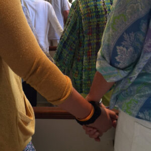 Congregants hold hands during a service at All Souls Unitarian Church, symbolizing unity and connection.