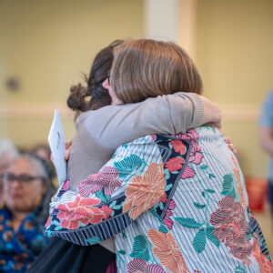 Two people share a warm embrace during a gathering at All Souls Unitarian Church, creating a sense of connection.