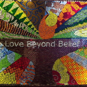 A colorful mosaic on the church wall spells out 'Love Beyond Belief,' symbolizing All Souls Unitarian Church’s inclusive mission.