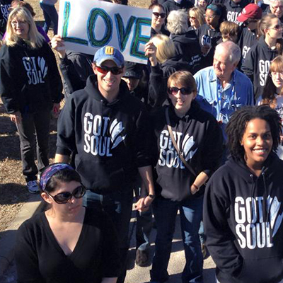 All Souls members in "Got Soul" hoodies participating in the Martin Luther King Jr. Day Parade holding a "Love" sign.