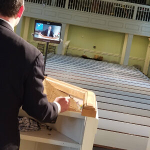 A church minister delivers a sermon via video screen to an empty sanctuary during the pandemic.