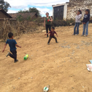 Children playing and kicking a plastic bottle in a rural area during the Sienna Project.