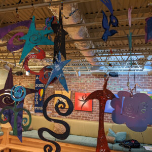 Colorful metal art pieces, including stars and swirls, hang from the ceiling in the Sponge Room at All Souls Unitarian Church.
