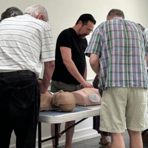 All Souls staff members practicing CPR techniques on mannequins during a training session.