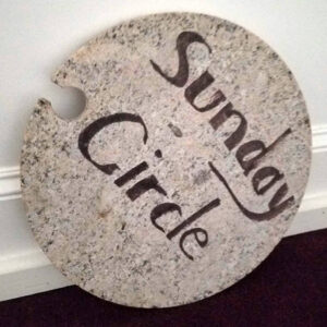A round sign reading 'Sunday Circle,' leaning against a wall at All Souls Unitarian Church.