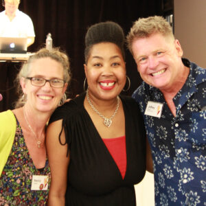 Three smiling All Souls Unitarian Church volunteers pose together at a volunteer appreciation event.