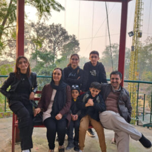 Dawood and his family posing outdoors with trees and towers in the background