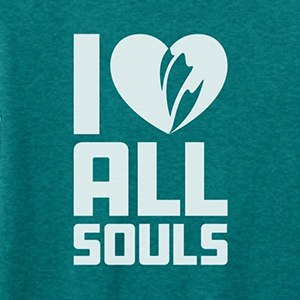 Close up on a green t-shirt that reads I (heart) All Souls, with the heart containing a flame logo.
