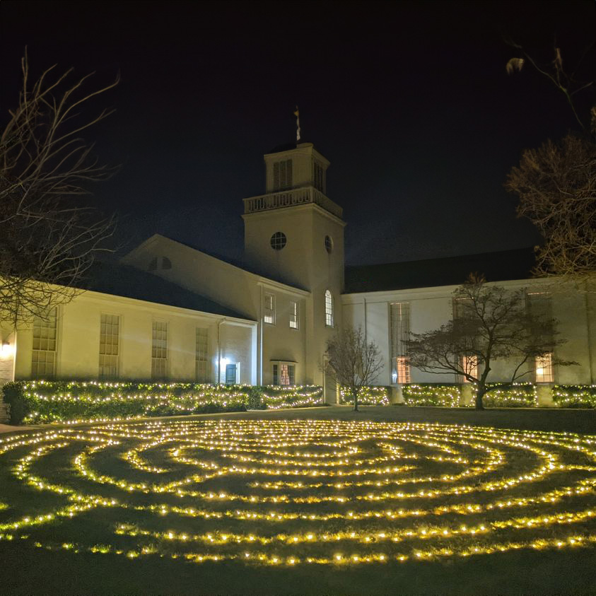A labyrinth created with Christmas lights, adorning a large lawn in front of a traditional, white church building.