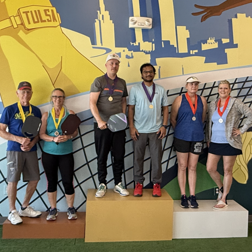 The top three teams stand on a podium together after the 2025 All Souls Pickleball fundraiser.